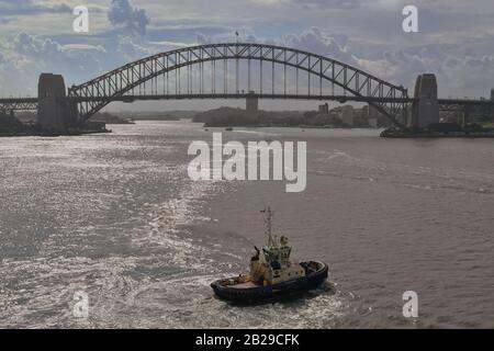 Sydney, NSW, Australia - 10 febbraio 2020: Rimorchiatore nel Porto di Sydney con Harbour Bridge sullo sfondo. Foto Stock