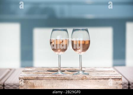 Due bicchieri di vino rosato su un piccolo tavolo di legno in primavera Foto Stock