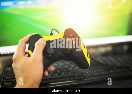 Giocatore e controller guy con joystick game pad a portata di mano giocando e guardando video su tv o Computer giochi console / il ragazzo che tiene hobby gioco Foto Stock