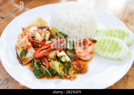 Mescolare pesce fritto gamberi calamari gamberi gamberi con basilico santo e riso / cibo tailandese piccante ricetta fritto con cetriolo e peperoncino Foto Stock