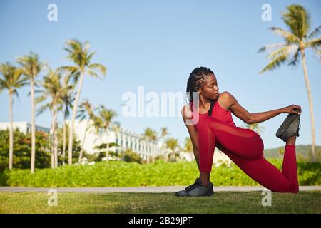 Pretty Young Black flessibile sportwoman gambe stretching dopo jogging nel parco Foto Stock