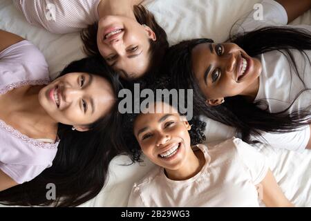 Vista dall'alto diverse donne migliori amici sdraiati a letto insieme Foto Stock