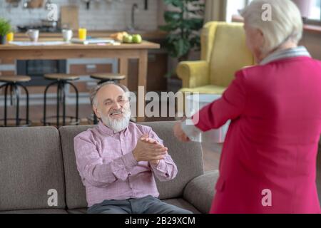 Signora anziana dai capelli grigi che dà un regalo al suo uomo Foto Stock