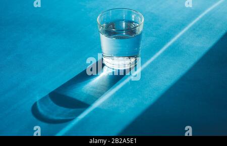 Acqua frizzante limpida in un vetro trasparente su sfondo blu Foto Stock