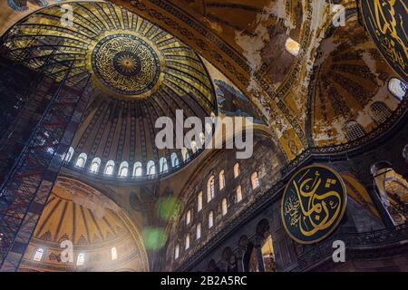 Cupola ornata e archi dipinti, con in seguito bandiere islamiche aggiunte, all'interno del Museo Hagia Sofia, Istanbul, Turchia Foto Stock