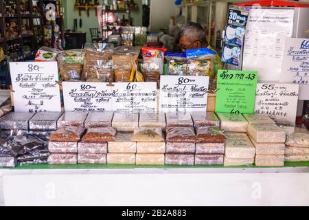 Pacchetti di diverse varietà di riso al di fuori di un negozio alimentare con segni di prezzo in tailandese e inglese, Thailandia Foto Stock