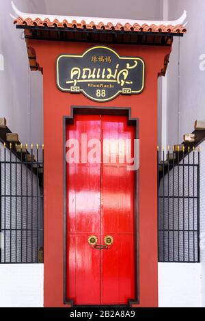 Tradizionale porta di legno rosso all'entrata di un ristorante, Phuket Old Town, Thailandia Foto Stock