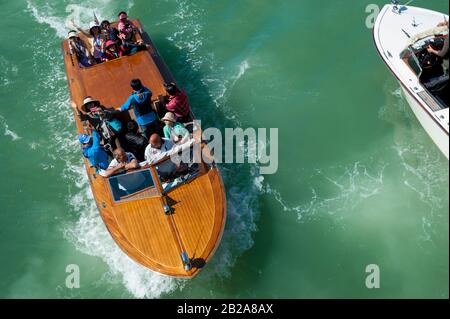 Venezia - 24 APRILE 2013: Un gruppo di turisti cinesi cavalcano un classico motoscafo italiano in mogano lungo il Canal Grande. Foto Stock