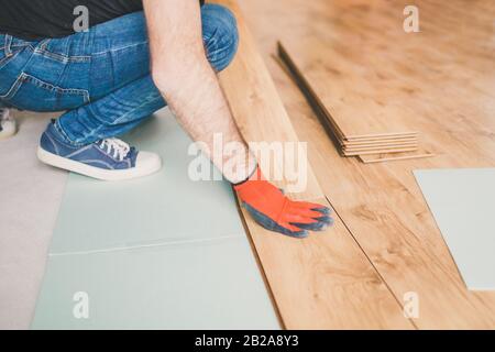 Un lavoratore installa un pavimento laminato durante il lavoro di finitura Foto Stock