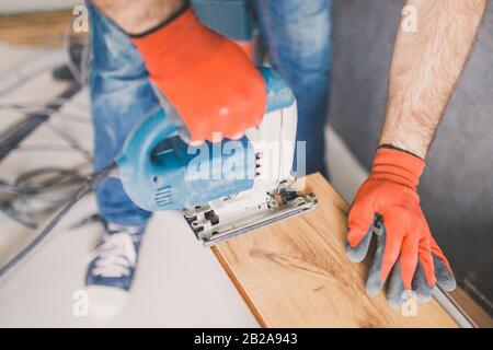 Un lavoratore installa un pavimento laminato durante il lavoro di finitura Foto Stock