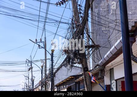 Cavi elettrici disordinati e disordinati che pendono da un polo elettrico in Thailandia Foto Stock