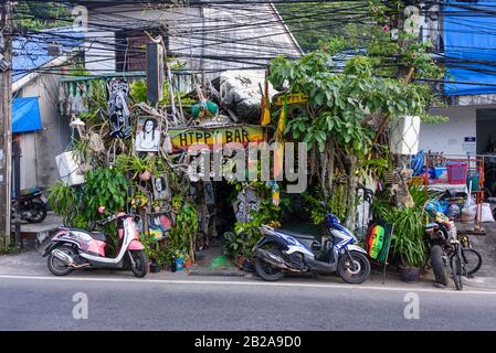 Cavi elettrici disordinati e disordinati che pendono da un polo elettrico all'esterno di un hippy Bar con le immagini e le piante di Bob Marley, Kata, Phuket, Thailandia Foto Stock