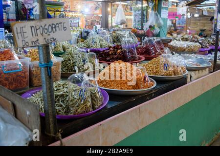 Ciotole di gamberetti cotti, gamberi, acciughe e bambini, con un segno che dice 'non gusto' in tailandese e inglese, per la vendita in una stalla alimentare a Thail Foto Stock
