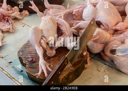 Grande sfaldatura su un tagliere di legno con un certo numero di carcasse di pollo ad un macellaio tailandese, Thailandia Foto Stock