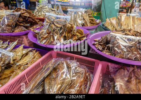 Sacchetti di plastica di pesce secco tailandese tradizionale in vendita presso uno stallo del mercato alimentare, Thailandia Foto Stock