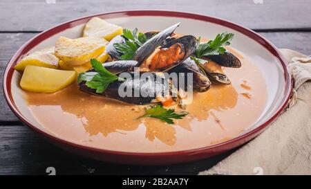 Banner alimentare. Cozze e patate fritte in salsa agrodolce su un tavolo di legno scuro. Foto Stock