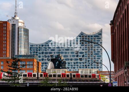 Amburgo, Germania - 4 agosto 2019: Paesaggio urbano panoramico di Amburgo con il treno che attraversa un ponte in primo piano e Elbphilharmonie nel backgroun Foto Stock