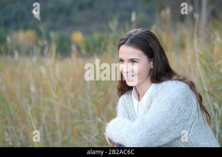 Ragazza felice teenage che indossa un maglione guardando via su un campo in inverno Foto Stock