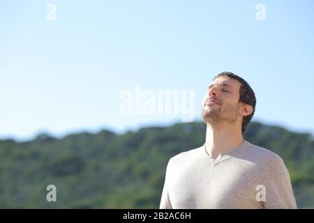 Uomo rilassato respirare aria fresca vicino alle montagne con un cielo blu sullo sfondo Foto Stock