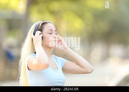 Concentrato ragazza adolescente ascolto di musica con uno sfondo parco in estate Foto Stock