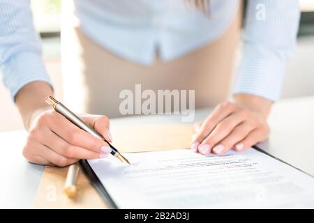 Donna d'affari che firma il documento di contratto sulla scrivania dell'ufficio, facendo un affare. Foto Stock