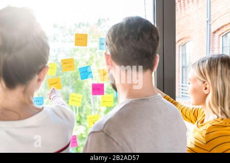 La gente di affari riunione in ufficio e uso di post-it per condividere idea. Concetto di brainstorming. Nota adesiva sulla parete di vetro. Foto Stock