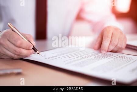 Uomo d'affari che firma il documento di contratto sulla scrivania dell'ufficio, facendo un affare. Foto Stock