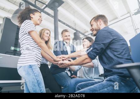Una visione ravvicinata dei giovani imprenditori che mettono insieme le mani. Pila di mani. Concetto di unità e lavoro di squadra. Foto Stock