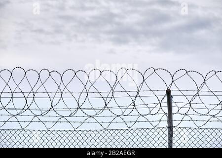 Primo piano di una recinzione ad alta catena con filo spinato sulla cima che protegge un aeroporto in Germania Foto Stock