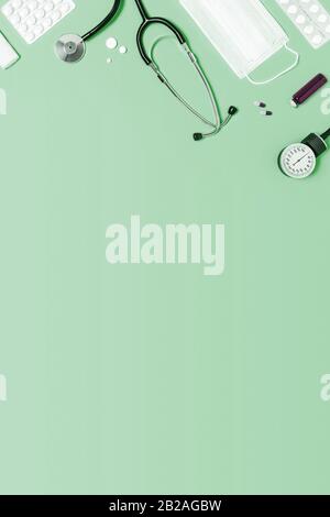 Fondo verde menta per uso medico con diversi accessori: Stetoscopio, termometro, siringa e compresse. Foto Stock