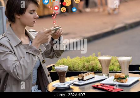 Ragazza blogger sedersi al tavolo del caffè prendere foto di cibo per instagram ottenere piace. Foto Stock