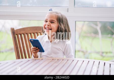 Una bambina usa lo smartphone del telefono cellulare a casa Foto Stock