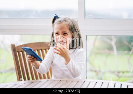 Una bambina usa lo smartphone del telefono cellulare a casa Foto Stock