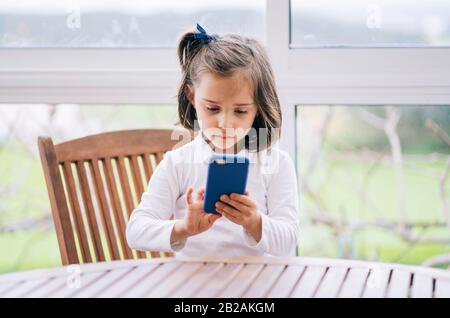 Una bambina usa lo smartphone del telefono cellulare a casa Foto Stock