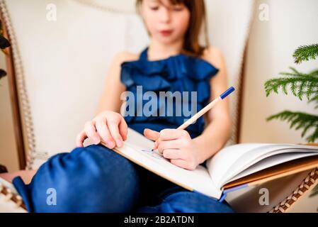 Ragazza seduta su una sedia facendo il suo lavoro Foto Stock