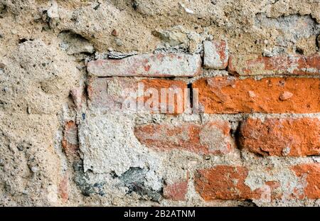 Foto di un vecchio muro di mattoni. I mattoni e mortat sono pesantemente testurizzati e weathered. Foto Stock