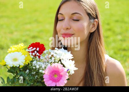 Ritratto di una giovane donna che profumava bouquet di fiori all'aperto Foto Stock