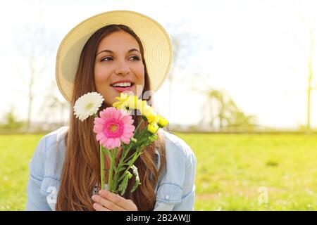 Felice ragazza sorridente con bouquet di fiori che guarda al lato esterno nel parco Foto Stock