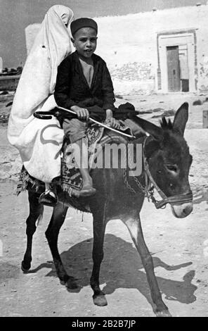 Un ragazzino e una donna completamente velata su un asino in Tunisia. Foto Stock