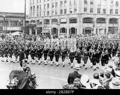 Un'unità di marinai giapponesi marches armati su una strada a Seattle nello stato di Washington negli Stati Uniti come parte delle celebrazioni che segnano l'indipendenza degli Stati Uniti il 4 luglio 1936. La strada è fiancheggiata su entrambi i lati da spettatori. Di fronte ai marinai guida un poliziotto su una moto. Foto Stock