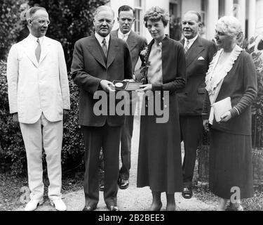 Amelia Earhart riceve una medaglia d'oro da J. Edgar Hoover per il suo volo transatlantico. Con lei nella Casa Bianca sono (da sinistra a destra): Dr. Gilbert Grosvenor, Präsident Hoover, George Palmer Putnam, Amelia Earhart, John O. la Gorce e la signora Hoover. Foto Stock