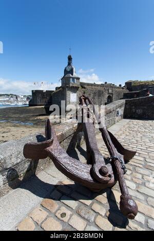 Città Di Concarneau, Francia. Vista pittoresca di un'ancora arrugginita sul ponte di Ville Close, con la medievale Ville Close sullo sfondo. Foto Stock