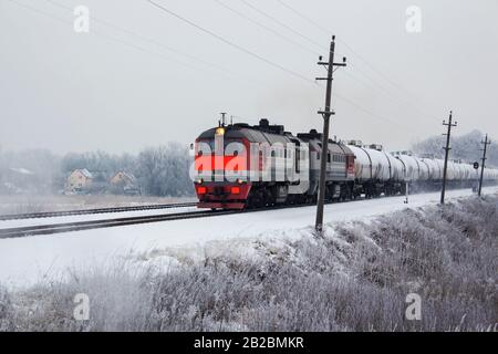 un treno arancione luminoso per il trasporto merci in movimento in inverno Foto Stock