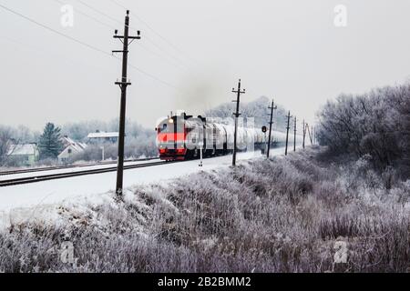 un treno merci arancione luminoso in movimento in inverno. Foto Stock