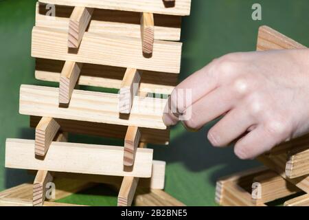 La torre da blocchi di legno e di mano d'uomo prendere un blocco Foto Stock