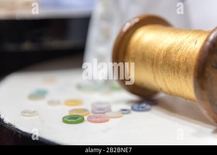 Bobina In Legno Con Filettatura Gialla Con Bottoni Assortiti E Bracciale Con Camicia Bianca Foto Stock