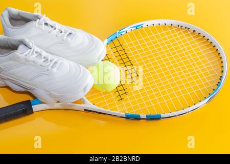 Racchetta da tennis con una palla e scarpe da ginnastica, su uno sfondo luminoso. Fotografato nello Studio Foto Stock