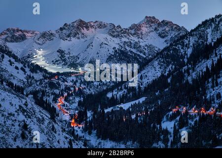 Paesaggio di strada incandescente da Medeu ghiaccio skate a Shymbulak stazione sciistica a Tian Shan montagna in serata a Almaty, Kazakistan Foto Stock