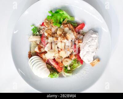 Caesar insalata in un piatto bianco su sfondo bianco. Foto Stock