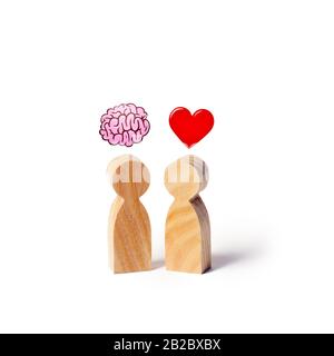 Due figure in legno con l'immagine del cervello e cuore. L'equilibrio tra amore e mente. La famiglia rispetto alla carriera o al lavoro. La psicologia della famiglia. Problema Foto Stock